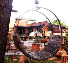 an old tire swing sitting in the middle of a yard next to potted plants