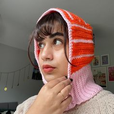 a woman wearing an orange and pink knitted hat with a hood on her head