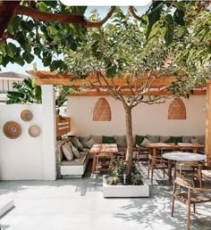 an outdoor seating area with tables, chairs and a tree in the middle of it