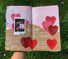 someone is holding an open book with hearts painted on it and the pages have been cut out