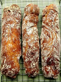 three loaves of bread sitting on top of a cooling rack