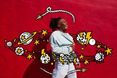 a woman standing in front of a red wall with stars and planets painted on it