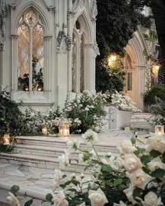 white roses and candles are on the steps in front of an ornate building with stained glass windows