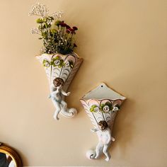 two wall mounted vases with flowers in them