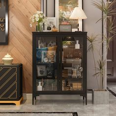 a black cabinet with glass doors and pictures on the wall behind it in a living room