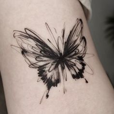 a black and white butterfly tattoo on the right side of the thigh, with ink splatters all over it