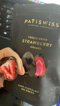 a person holding up a chocolate covered strawberry