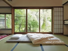 an empty room with tatami mat and window overlooking the trees outside in front of it