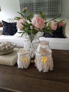 a table topped with candles and flowers on top of a wooden table next to a white couch