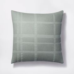 a light green pillow on a white wall with a checkered pattern in the middle