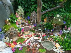 a garden with lots of plants and small houses on it's sides, surrounded by rocks