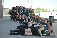 a group of young women in green uniforms posing for a photo with each other on the ground