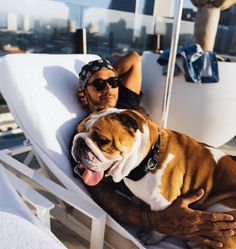 a man laying on top of a white chair next to a brown and white dog