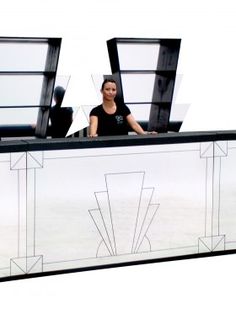 a woman sitting at a desk with three windows on it's sides and an abstract design behind her