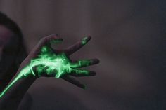 a woman is holding her hand up with glowing green paint on the palm and fingers