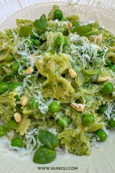 a white plate topped with green vegetables covered in parmesan sprouts and shredded cheese