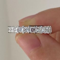 a person holding a ring with five princess cut diamonds in it's middle finger