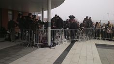 a group of people standing behind a metal fence