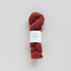 a skein of red yarn sitting on top of a white surface with a tag