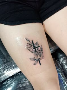 a cross and roses tattoo on the leg