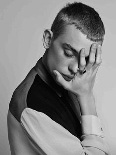 black and white photograph of a young man holding his hand to his face with both hands