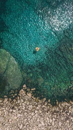 an aerial view of the ocean with rocks and green water in the foreground, from above