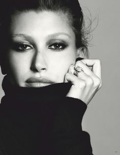 a black and white photo of a woman with her hand on her face, wearing a ring