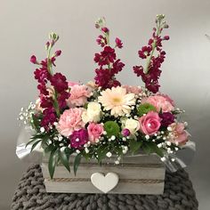 a heart - shaped box filled with pink and white flowers on top of a blanket