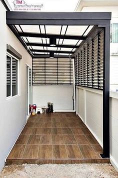 an outdoor covered patio with wood flooring and white walls on the side of it