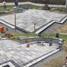 several men are working on the construction of an outdoor area with concrete blocks and pavers