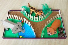 a cardboard box filled with different types of animals and plants on top of a wooden table