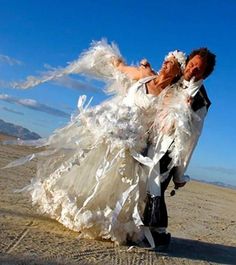 a man and woman dressed in white are dancing on the beach with their arms around each other