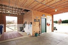 the inside of a garage with wood paneling and doors open to reveal an outdoor area