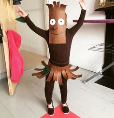 a child in a costume made to look like a tree man standing on a red mat