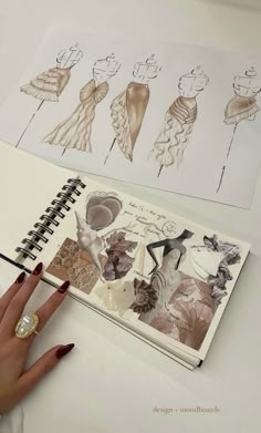 a woman's hand is holding a pencil and sketching on a notebook next to some drawings