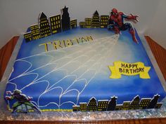 a spiderman birthday cake with the name tritan on it and cityscape in the background