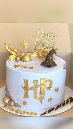 a harry potter themed birthday cake with gold decorations on it's top and the words happy birthday hp