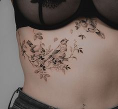 a woman's stomach with birds and flowers on the side, under her bra