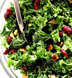 a salad with broccoli, cranberries and nuts in a glass bowl