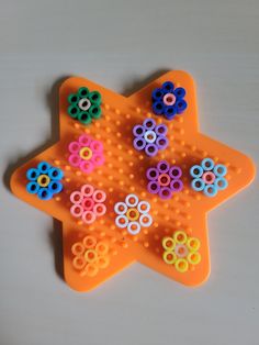 an orange plastic star shaped object with colorful beads on it's center and sides