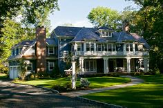 a large house in the middle of a lush green yard with trees and shrubs surrounding it