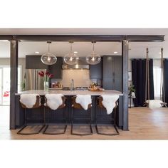 an open concept kitchen and dining area with marble counter tops, stainless steel appliances and hanging lights