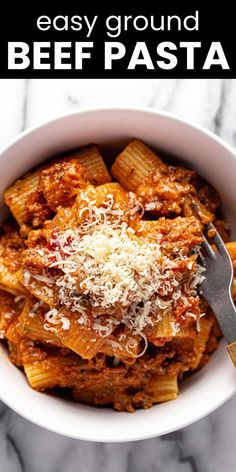 a white bowl filled with pasta and sauce on top of a marble table next to a fork