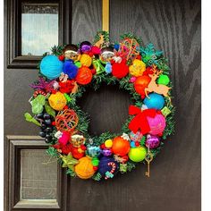 a colorful wreath is hanging on the front door with ornaments around it and an ornament in the center