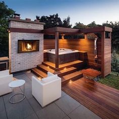 a hot tub sitting on top of a wooden deck next to a white chair and table