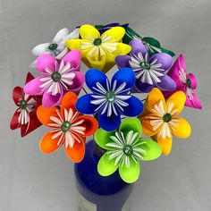 a blue vase filled with colorful paper flowers