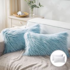 two fluffy blue pillows sitting on top of a bed