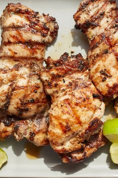 three pieces of meat sitting on top of a white plate next to sliced green peppers