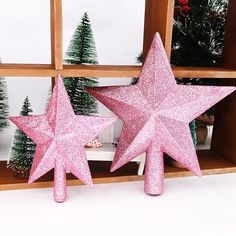 two pink glitter star decorations in front of a window