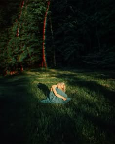 a woman is sitting in the grass with her head on her hands and eyes closed